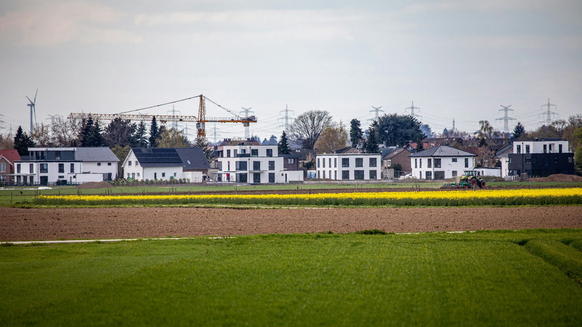 16.04.2021, Pulheim: Neu errichtete Wohnhäuser stehen am Ortsrand des Ortsrandes von Sinnersdorf während im Vordergrund landwirtschaftliche Felder zu sehen sind. Die Nachfrage nach Immobilien ist groß. Einfamilienhäuser stehen dabei wegen des hohen Flächenverbrauchs in der Kritik. Foto: Matthias Heinekamp