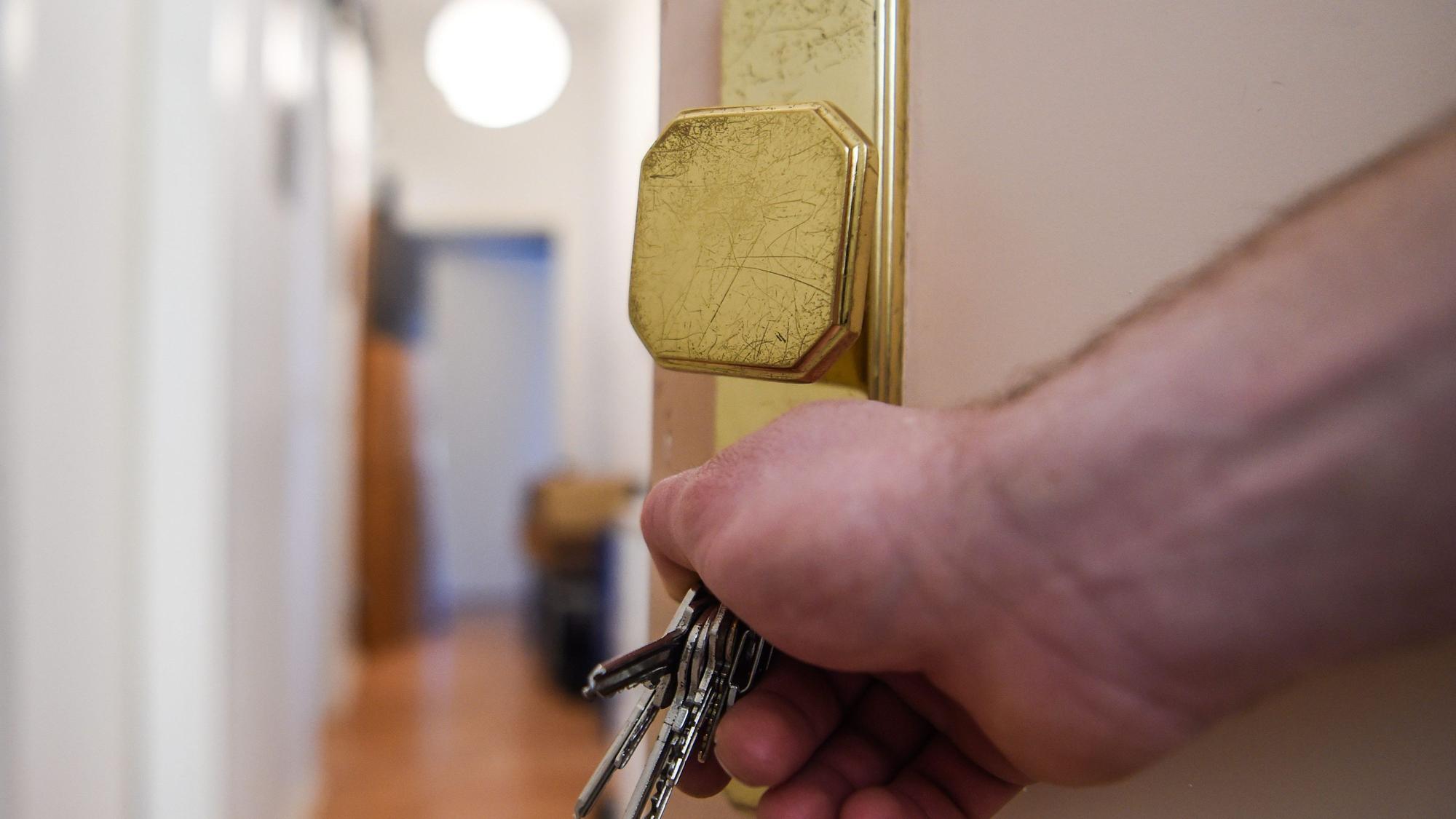 Ein Mann schließt die Tür zu einer Wohnung auf.