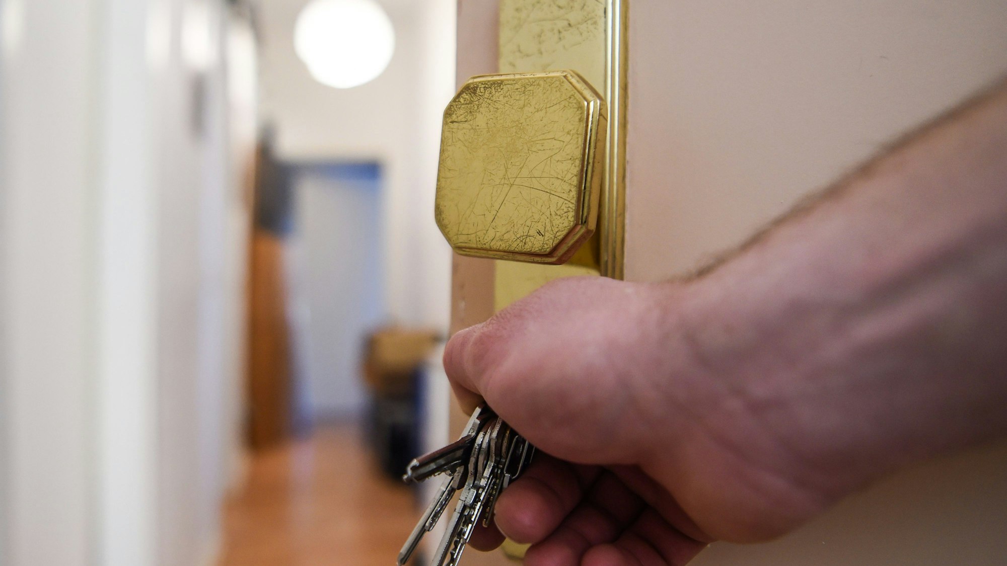 Ein Mann schließt die Tür zu einer Wohnung auf.