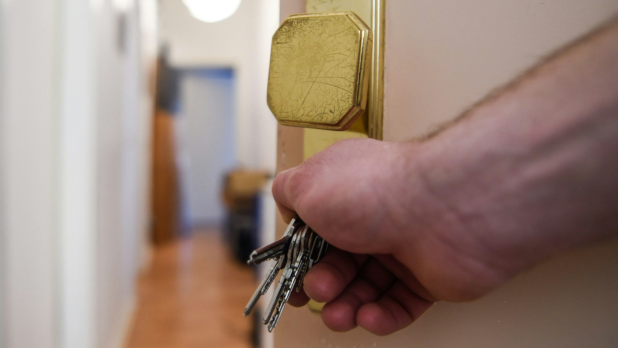 Ein Mann schließt eine Wohnungstür auf und öffnet sie.