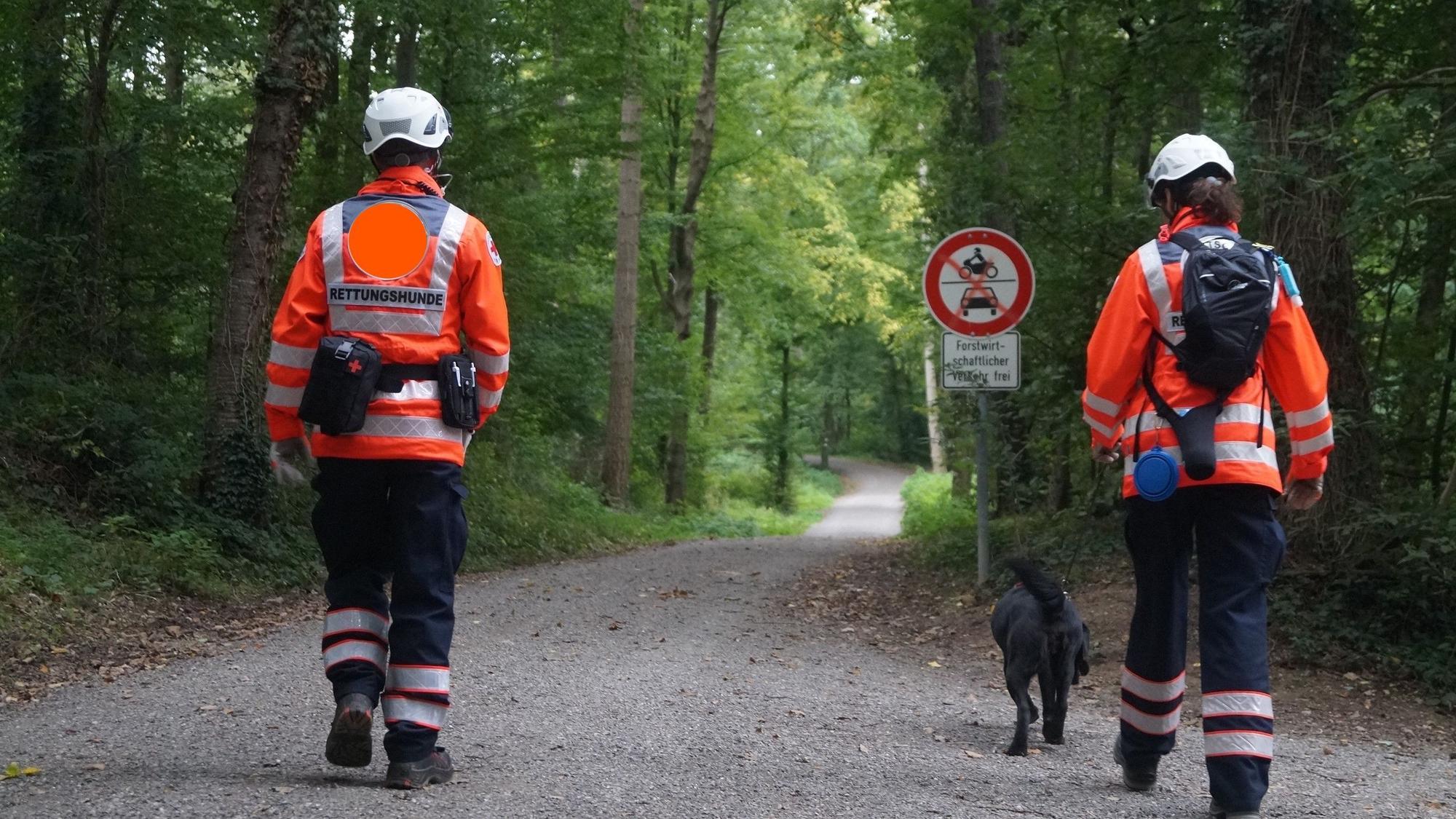 Auf dem Foto sind zwei Hundeführer mit einem Rettungshund zu sehen.