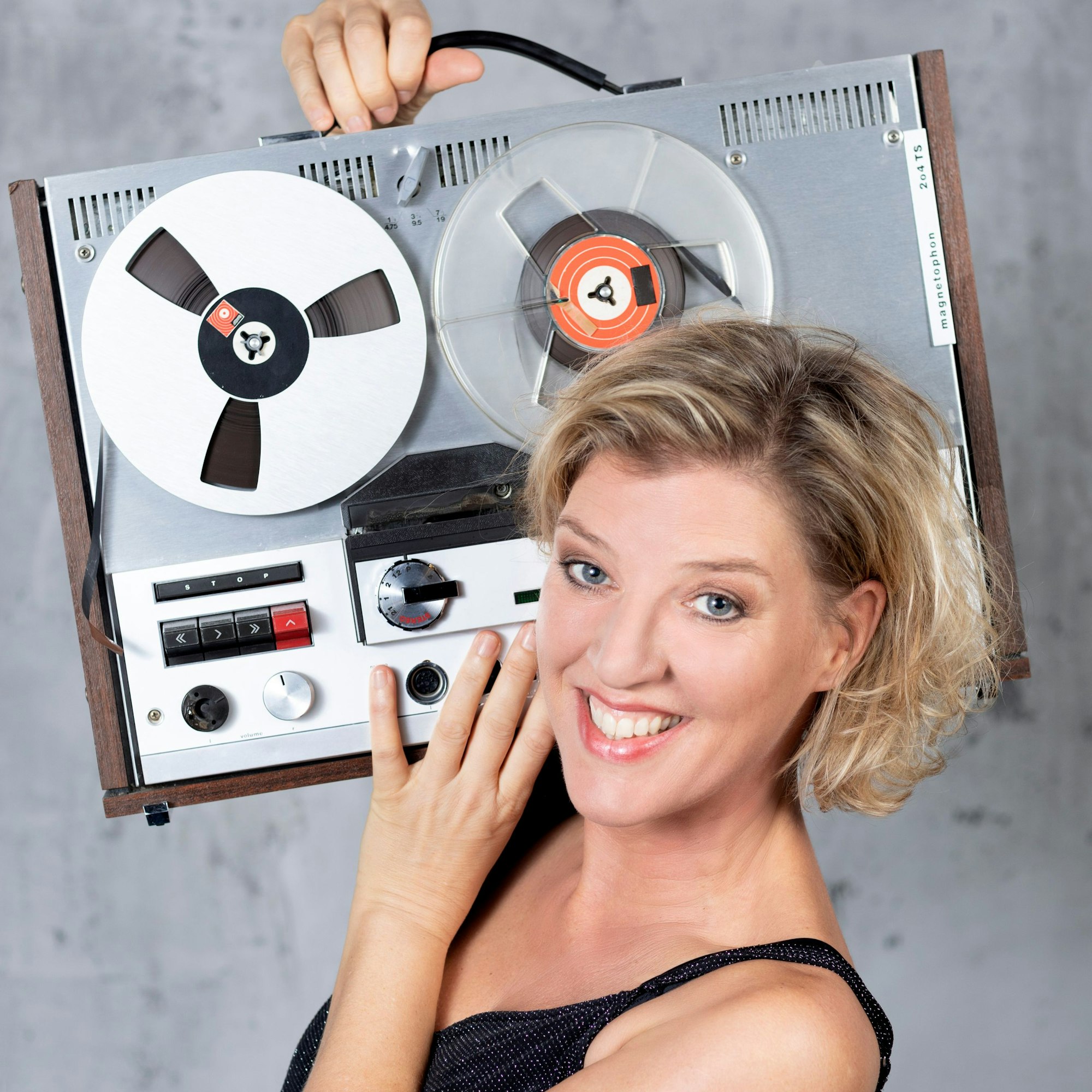 Das Foto zeigt die Künstlerin Sia Korthaus. Auf ihrer Schulter trägt sie ein Tonbandgerät.