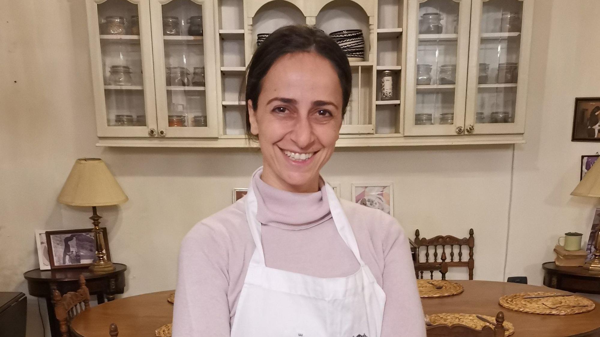 Frau in einem rosa Rollkragenpulli mit Kochschürze