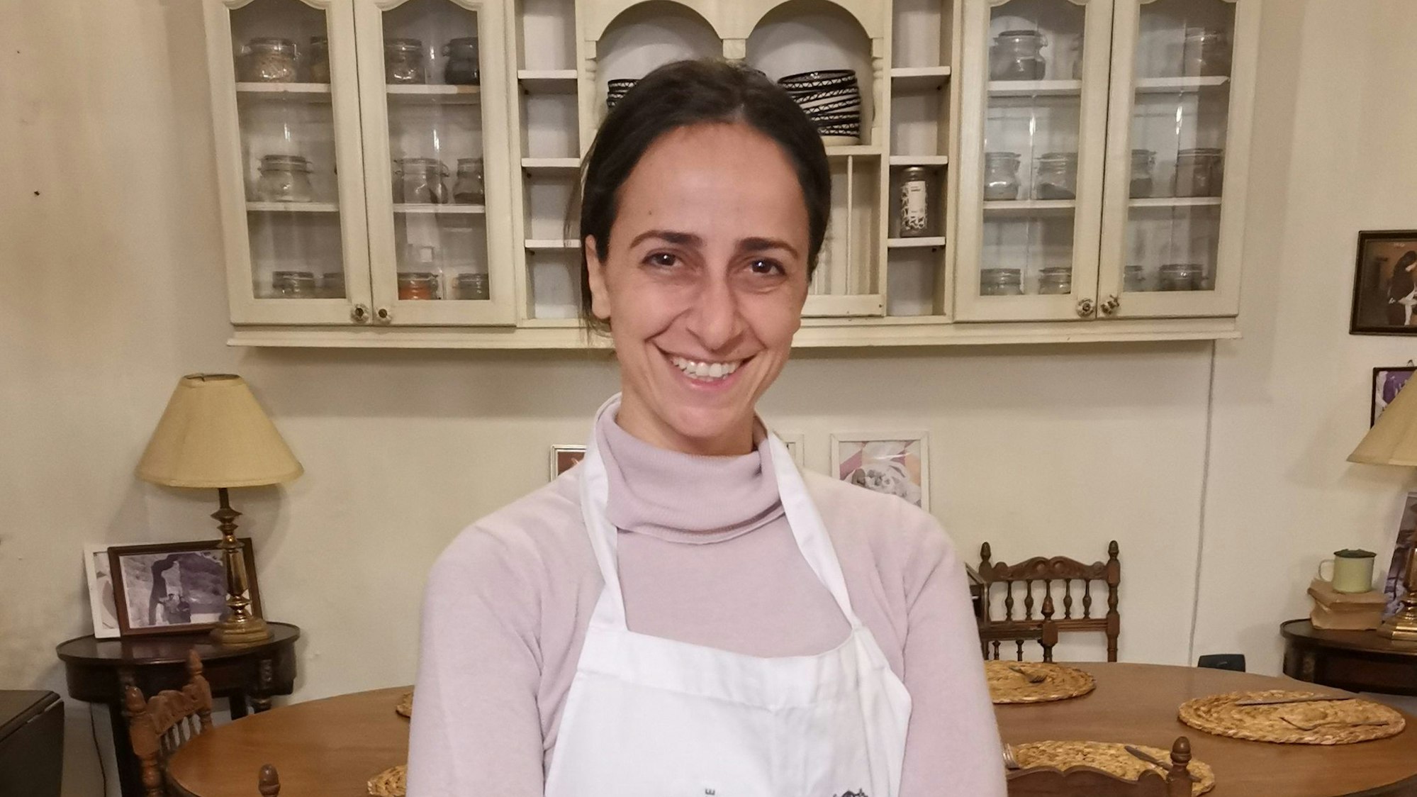 Frau in einem rosa Rollkragenpulli mit Kochschürze