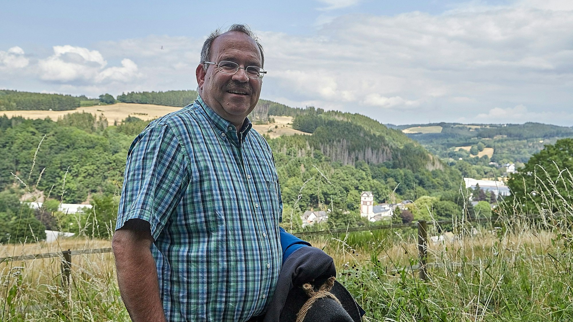 Ralf Nolten wandert in der Eifel. Im Hintergrund ist Hellenthal zu erkennen.