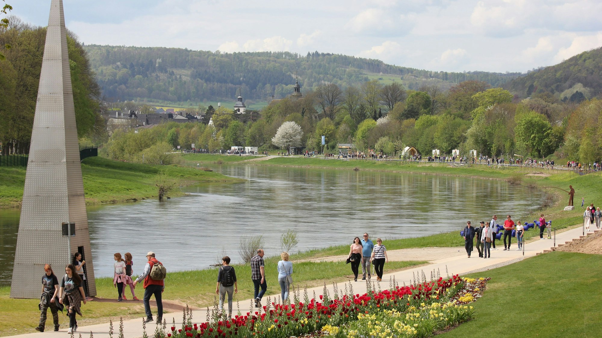 Am Ufer eines Flusses spazieren Menschen.