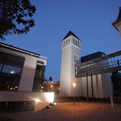 Historische und moderne Gebäude stehen auf dem Campus-Gelände, das in der Dämmerung beleuchtet ist,