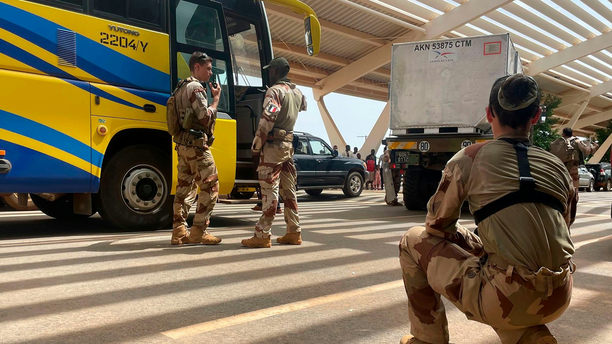 Französische Soldaten stehen neben einem Bus, der französische Staatsangehörige zum Flughafen bringt, von wo sie mit einem Militärflugzeug nach Frankreich geflogen werden sollen.