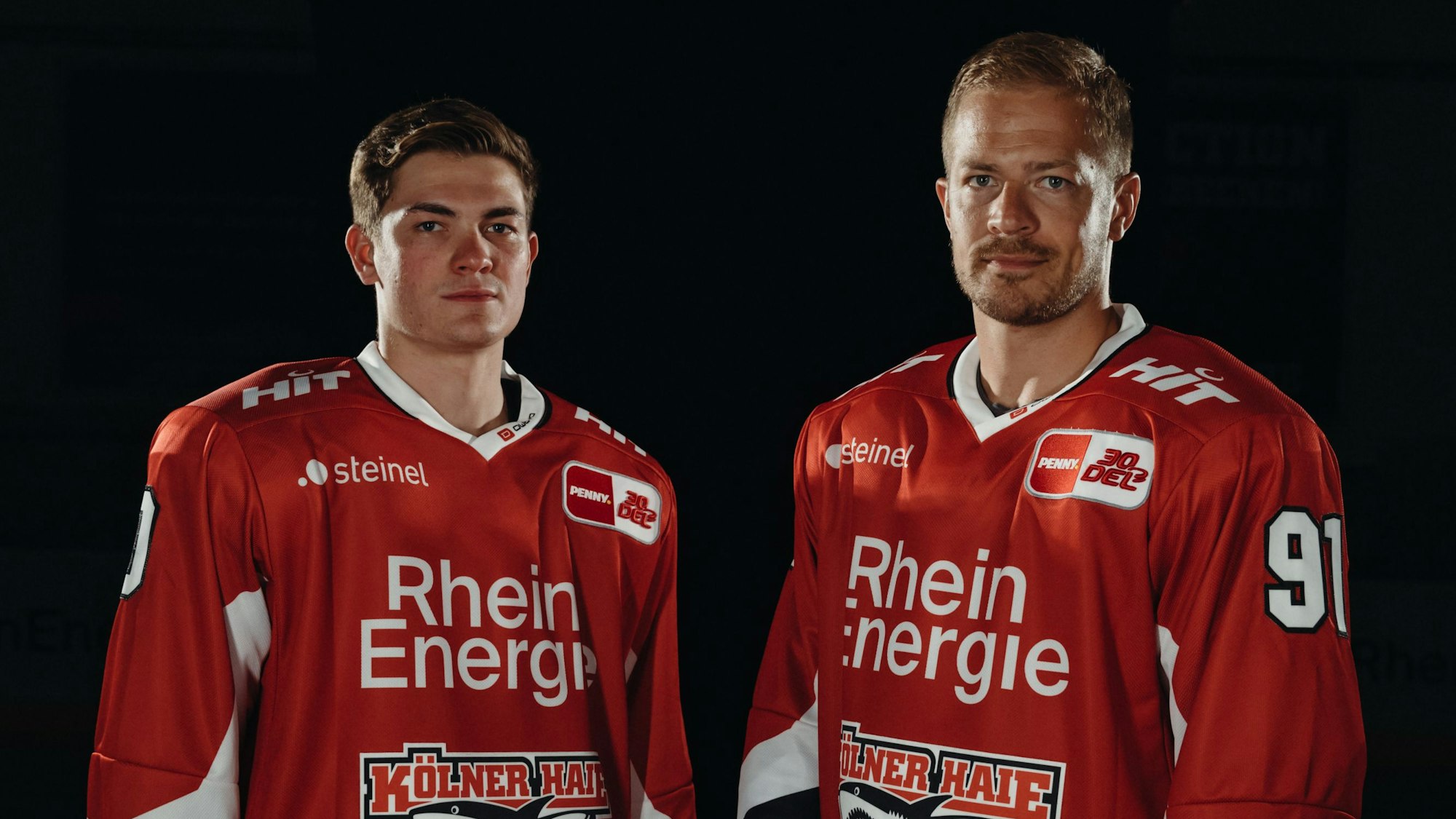 Neuzugang Justin Schütz (l.) und KEC-Kapitän Moritz Müller präsentieren das neue Heimtrikot der Kölner Haie.