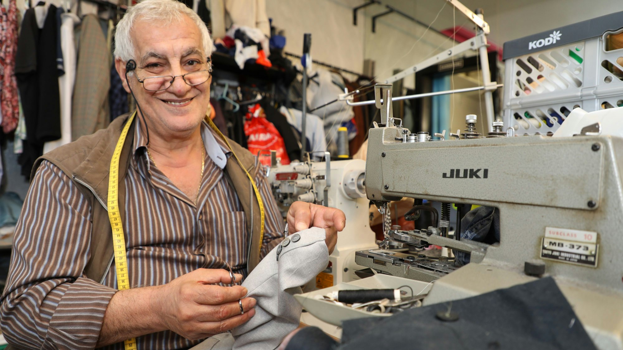 Der Schneider Fehmi Yilmaz sitzt an der Nähmaschine in seinem Änderungsstudio an der Bensberger Schloßstraße.