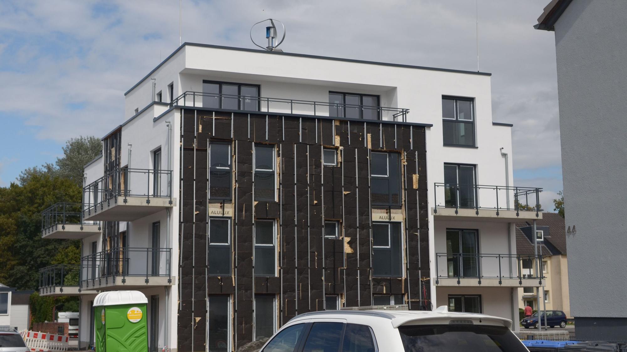 Das Bild zeigt die Fassade eines Neubaus, an der Photovoltaik-Module angebracht werden.