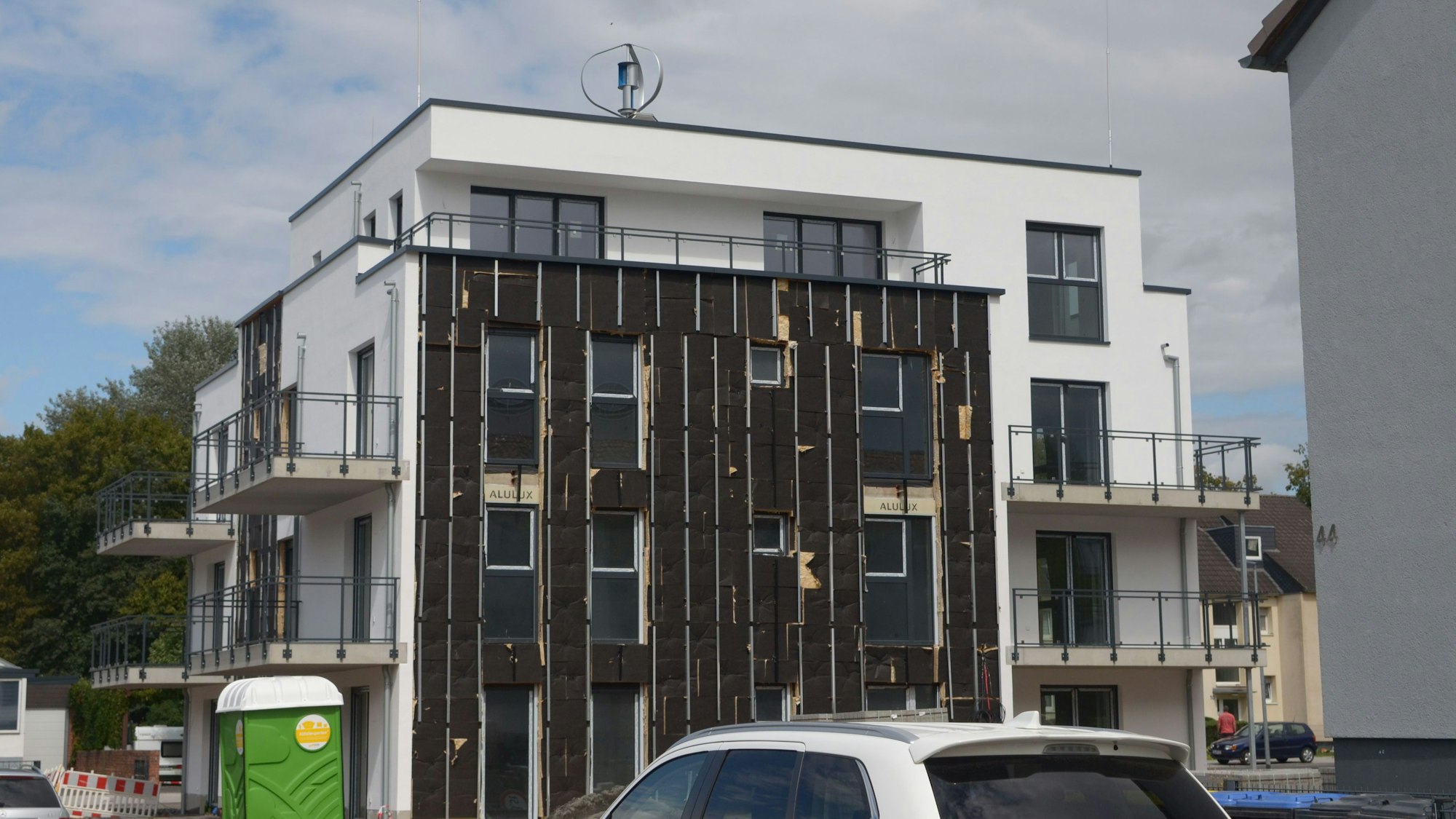 Das Bild zeigt die Fassade eines Neubaus, an der Photovoltaik-Module angebracht werden.