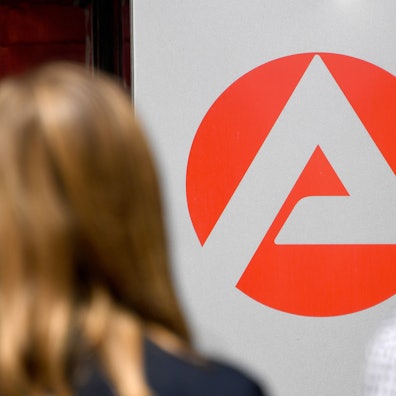 Zwei Personen stehen vor dem Logo der Agentur für Arbeit.
