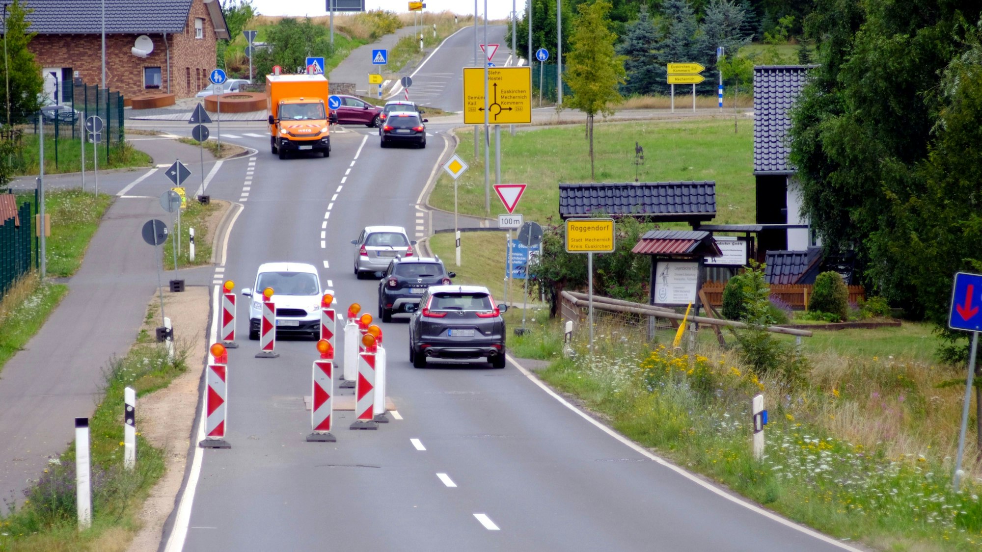 Die Fahrbahn einer Straße ist auf einer Seite mit Warnbaken abgesperrt, der Gegenverkehr muss warten.
