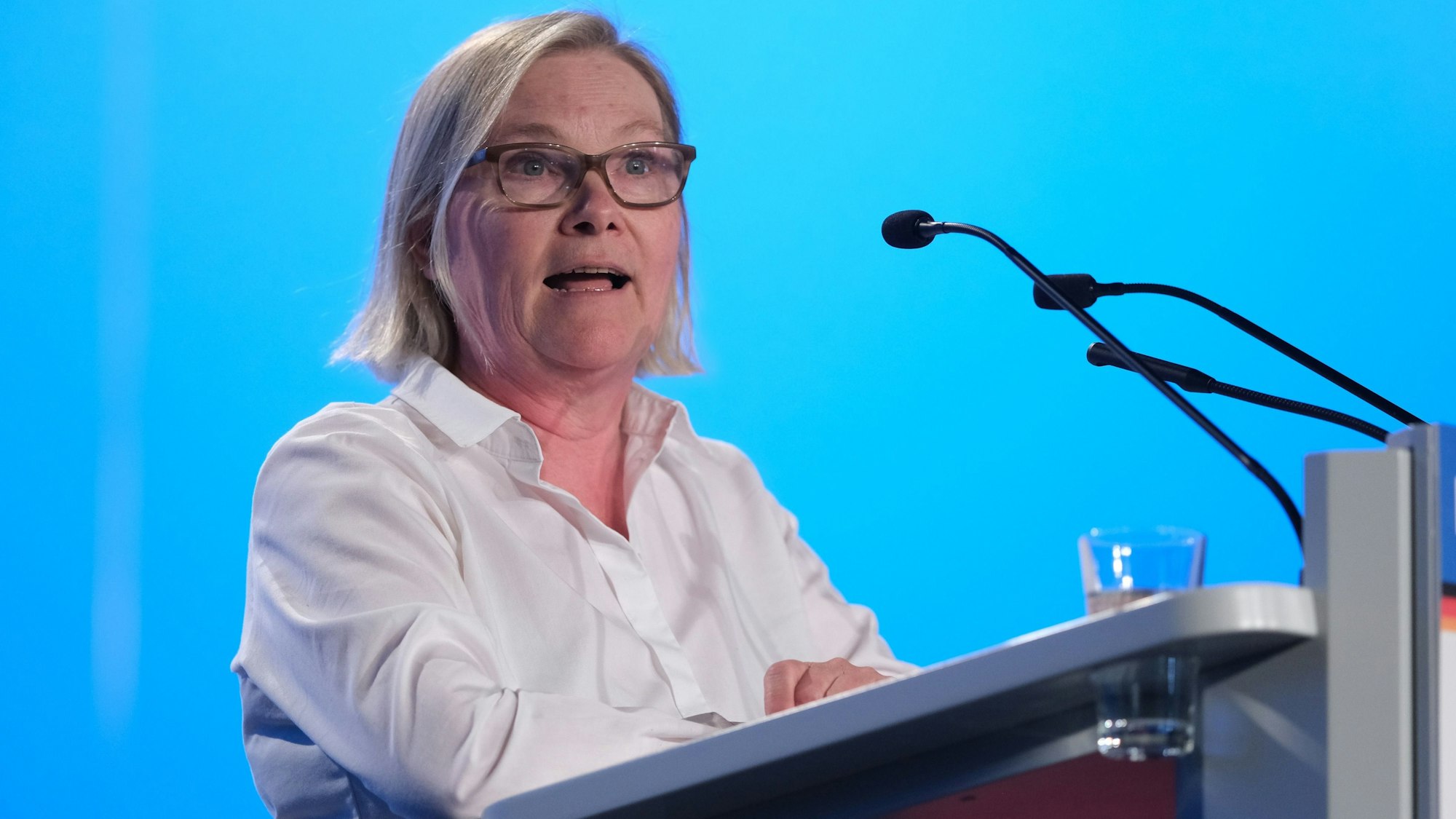 Irmhild Boßdorf, Bewerberin um einen Listenplatz der AfD für die Europawahl, spricht auf der AfD-Europawahlversammlung in der Messe Magdeburg. Sie trägt Brille und eine weiße Bluse und steht am Rednerpult vor der blauen Kulisse.
