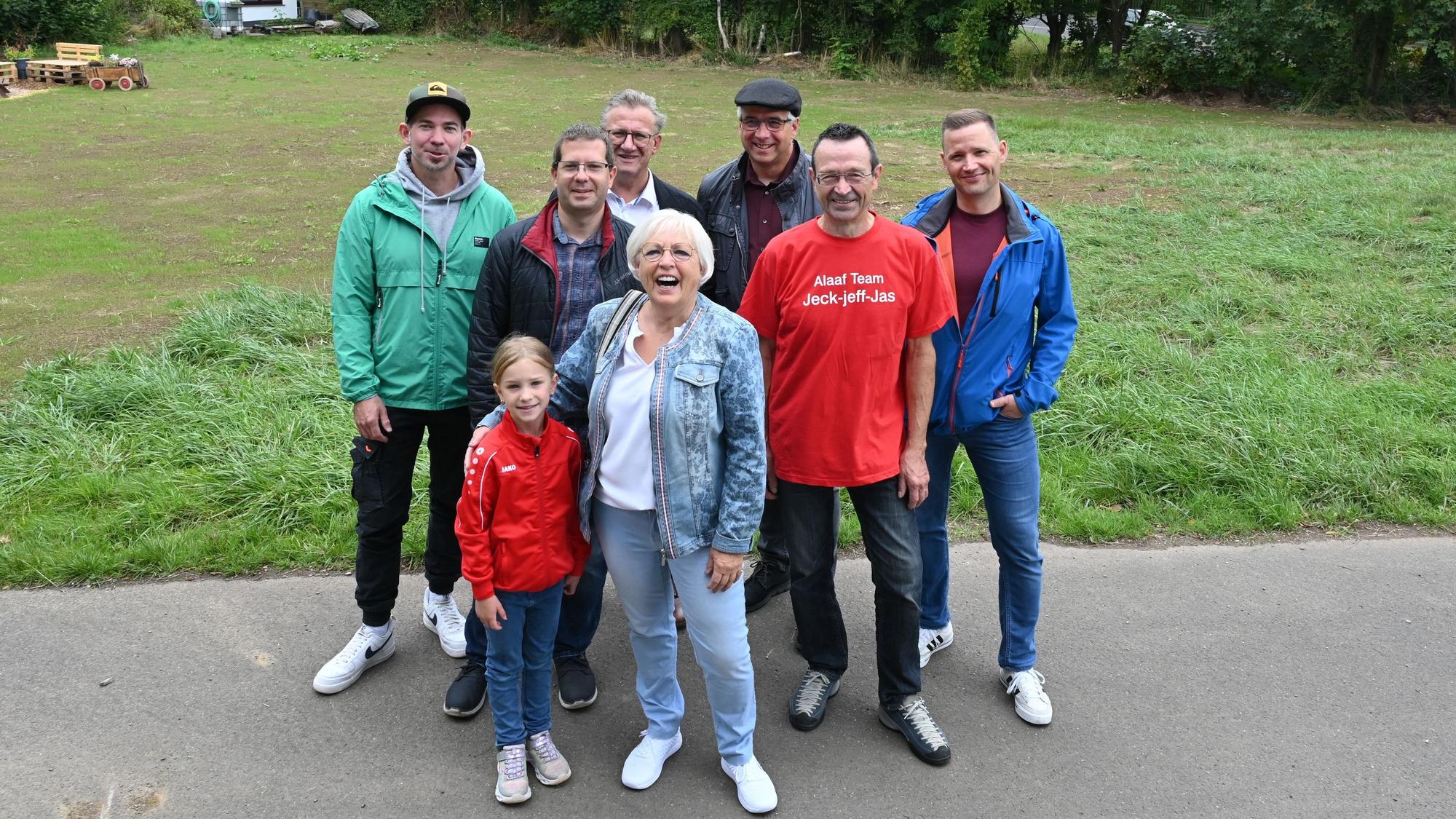 Eine Gruppe Menschen steht vor einer Wiese. Dort hat bis zur Flut das Vereinsheim des Gemünder Karnevalsvereins gestanden.
