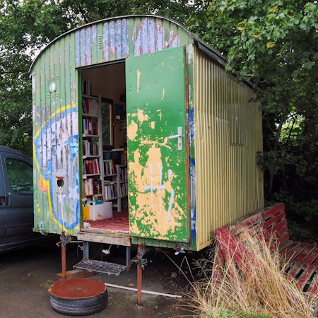 Ein Bauwagen steht unter einem Baum.