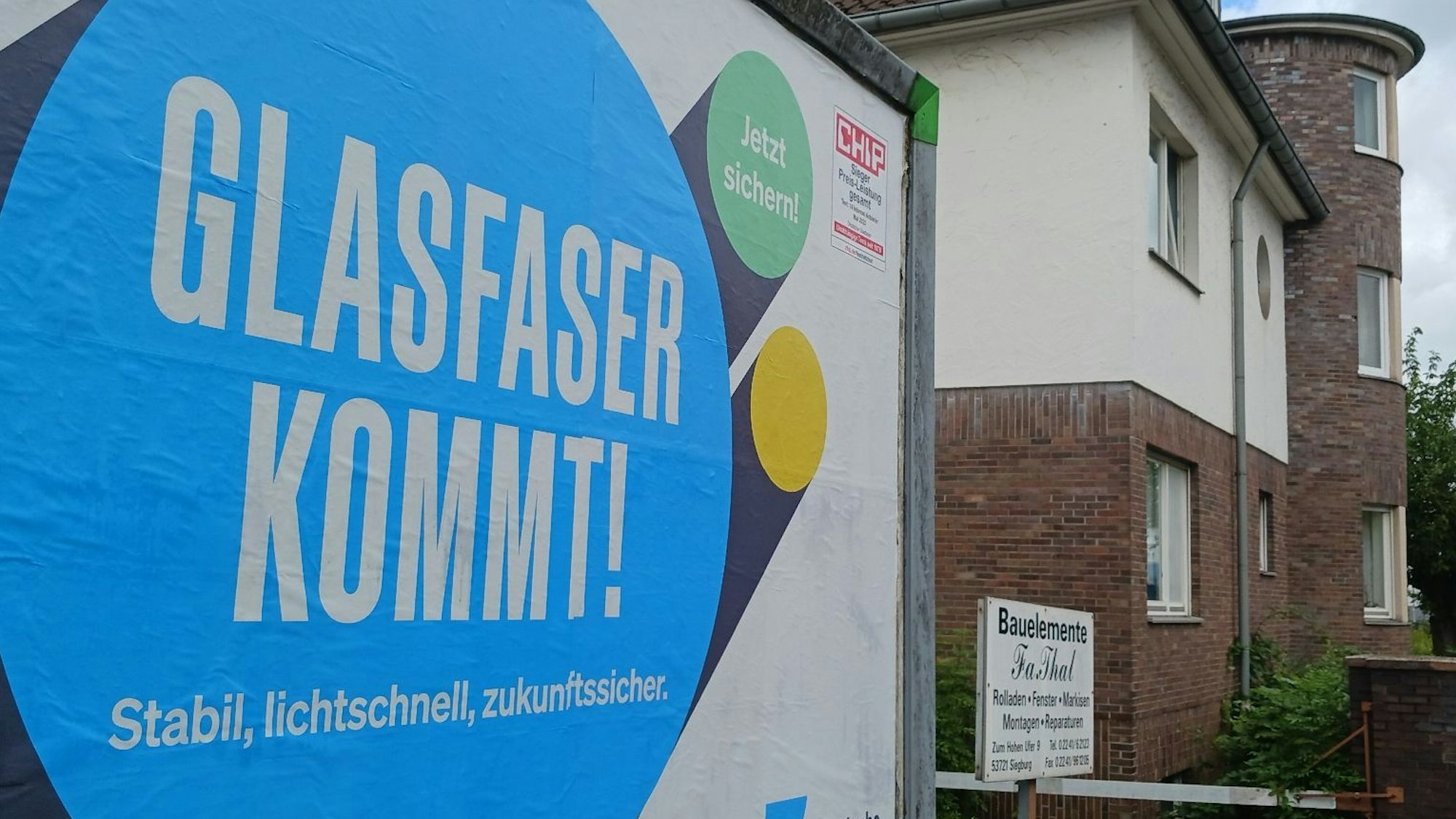 Ein Werbeplakat der Firma Deutsche-Glasfaser wirbt an einer Straße in Siegburg für Glasfaseranschlüsse