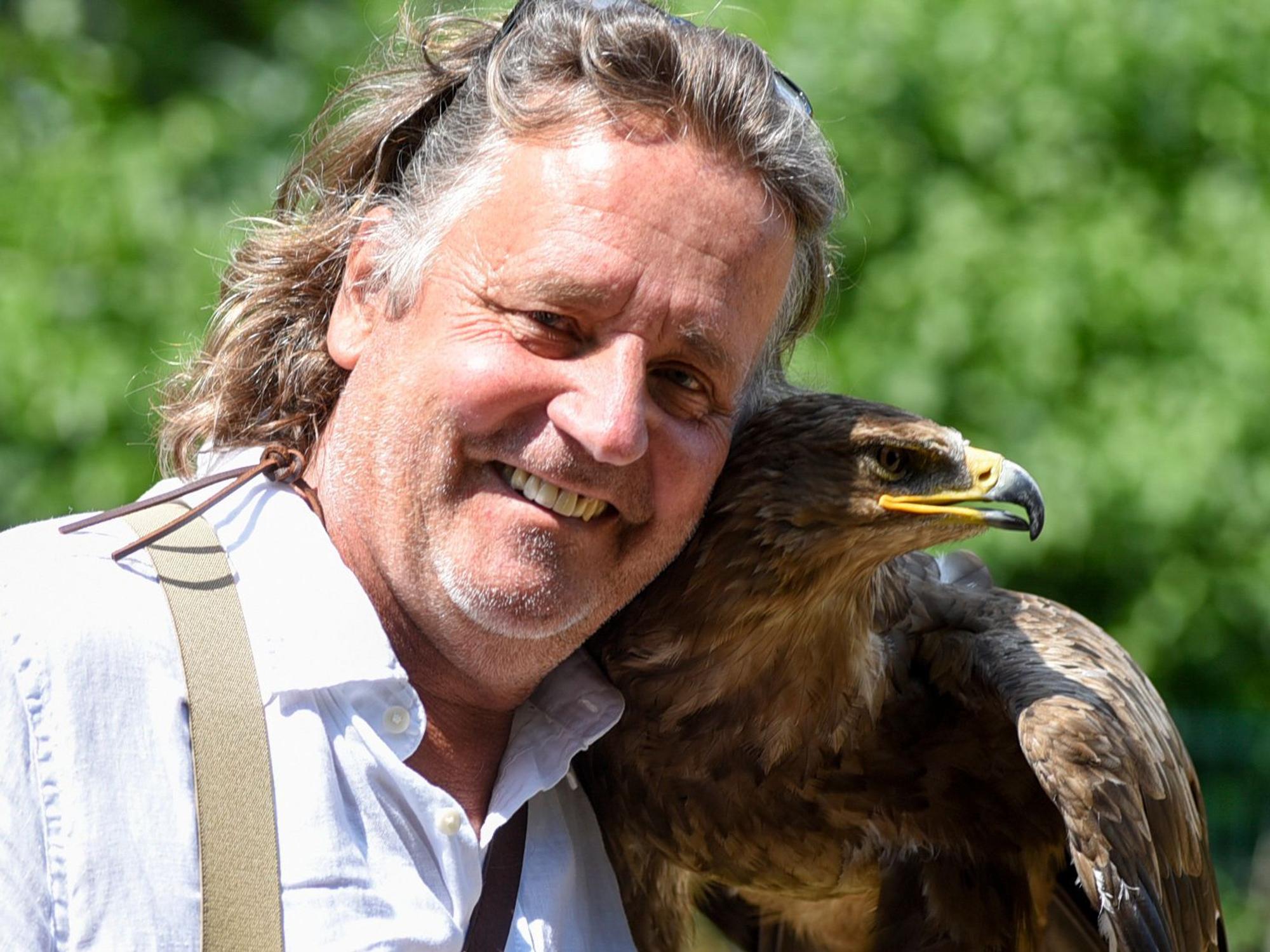 Ein Mann schaut lächelnd in Kamera, neben sich einen Adler.