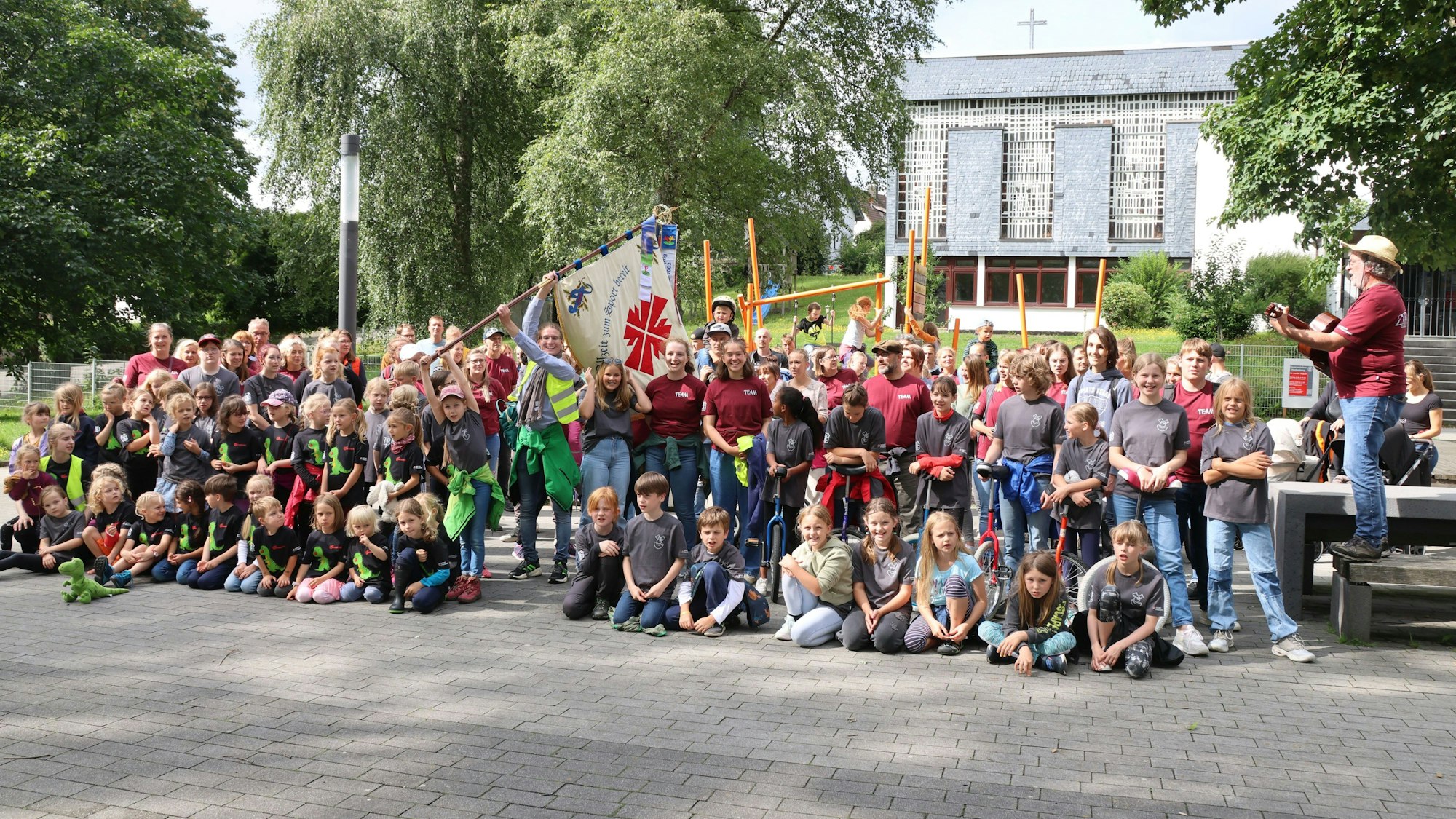 Die große Zirkusgruppe singt mit Gitarrenbegleitung.