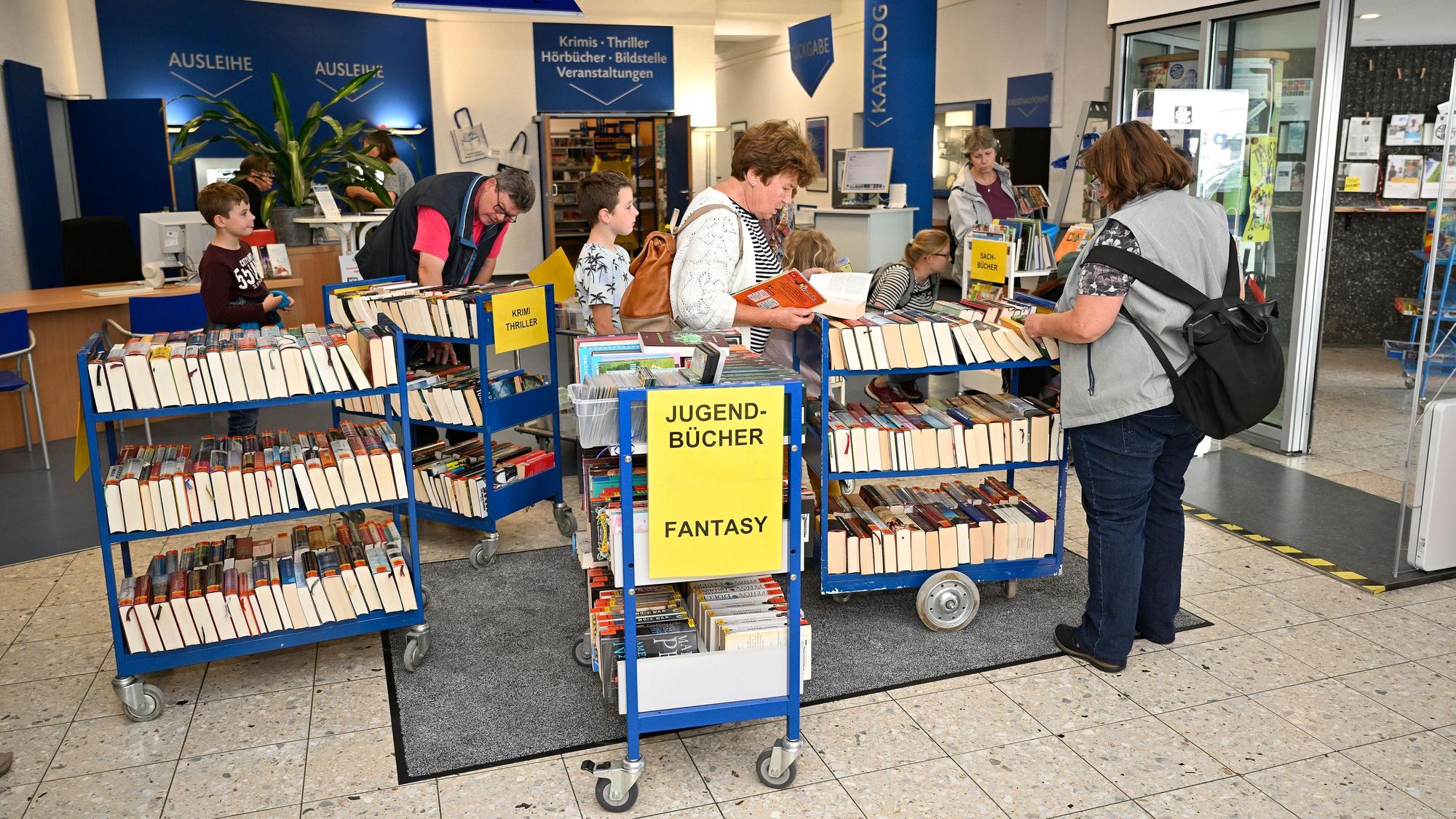 Menschen stöbern auf dem Medienflohmarkt in Büchern.