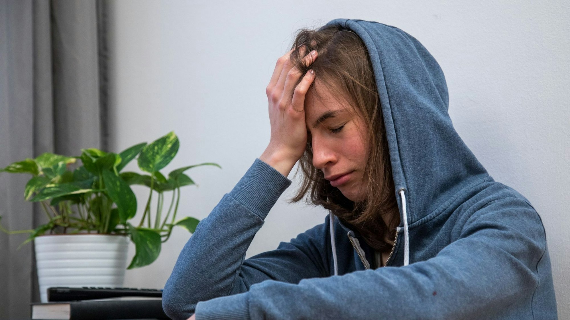 Eine junge Frau hält sich die Hand an den Kopf und guckt betrübt.
