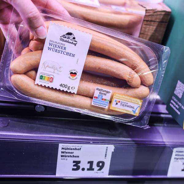Zwei Preisschilder hängen im Kühlregal vor einer Packung mit Wiener Würstchen.