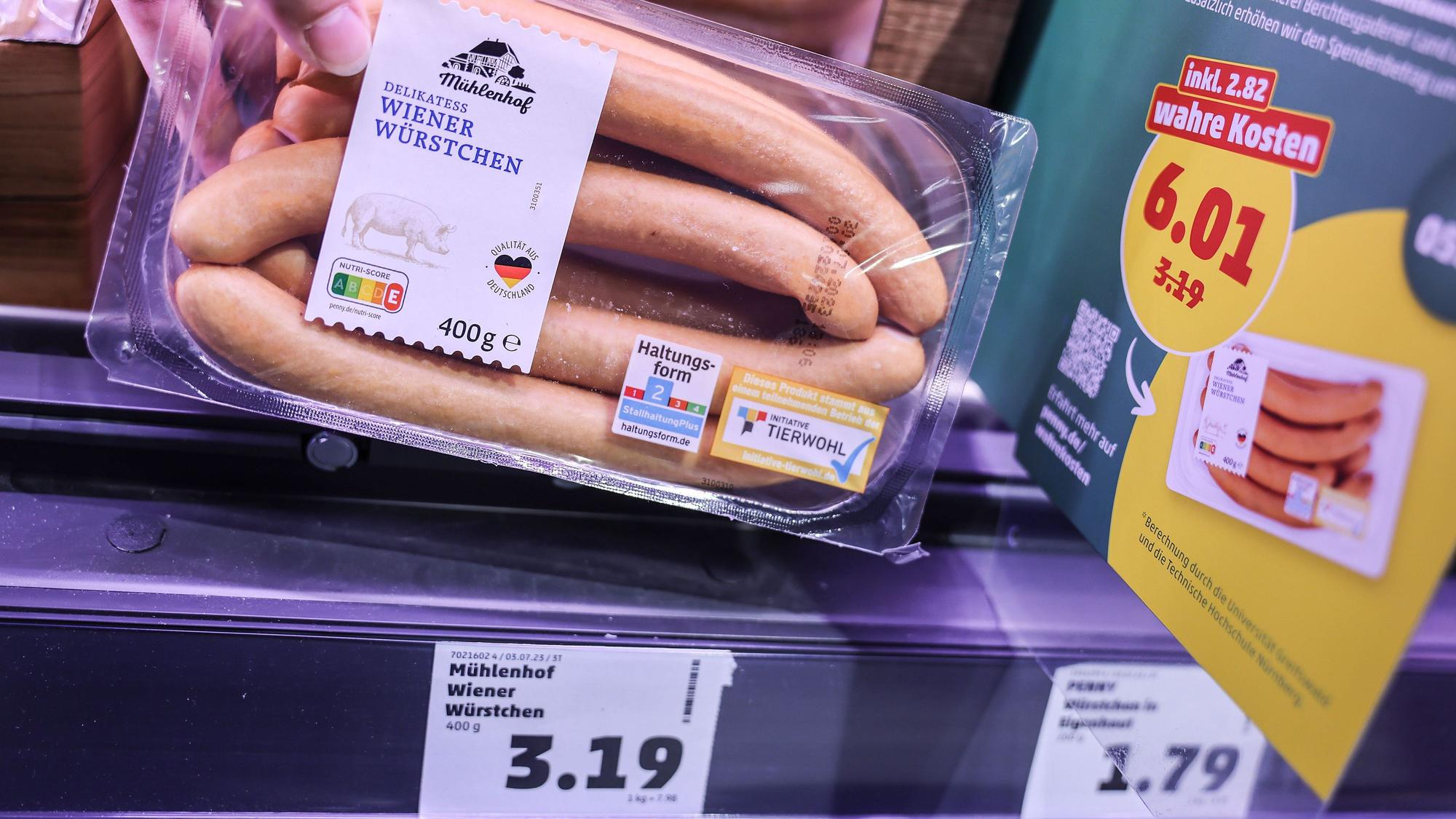 Zwei Preisschilder hängen im Kühlregal vor einer Packung mit Wiener Würstchen.
