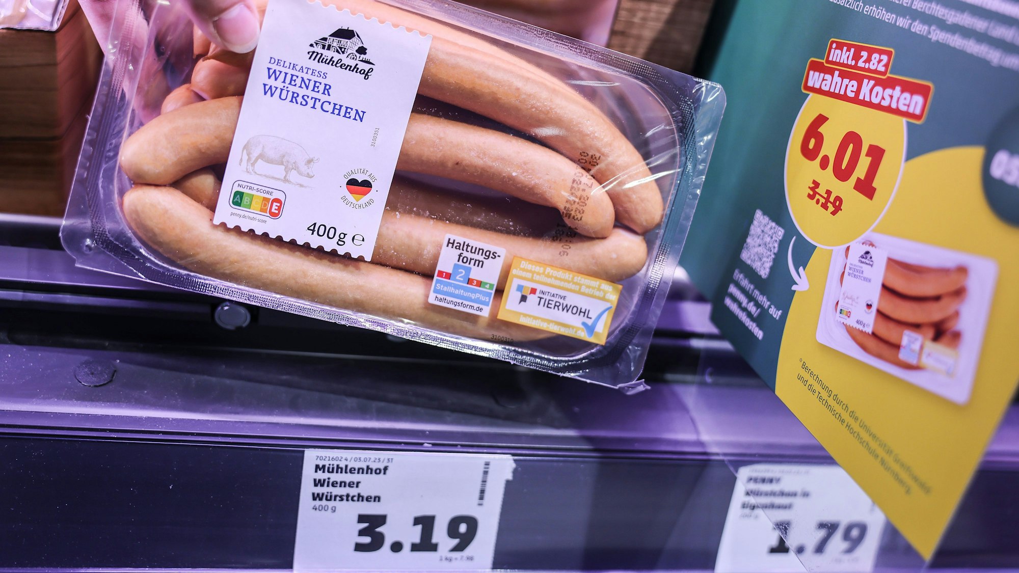 Zwei Preisschilder hängen im Kühlregal vor einer Packung mit Wiener Würstchen.
