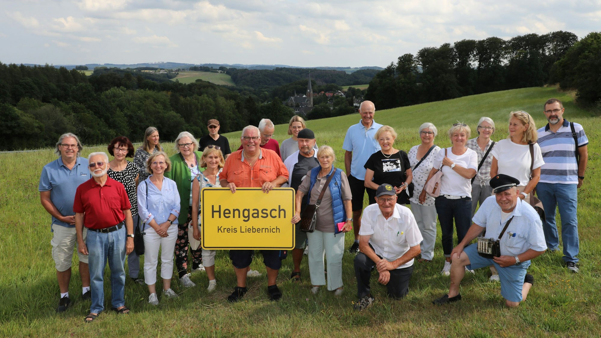 Eine Lesergruppe steht mit Vertretern der Redaktion und einem Ortsschild von Hengasch auf einer Wiese oberhalb der Ortes Kürten-Olpe.