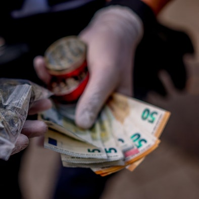 Ein Polizist zeigt eine sichergestellte Tüte Haschisch und Drogengeld während einer Razzia der Polizei gegen Drogendealer am Ebertplatz in Köln.