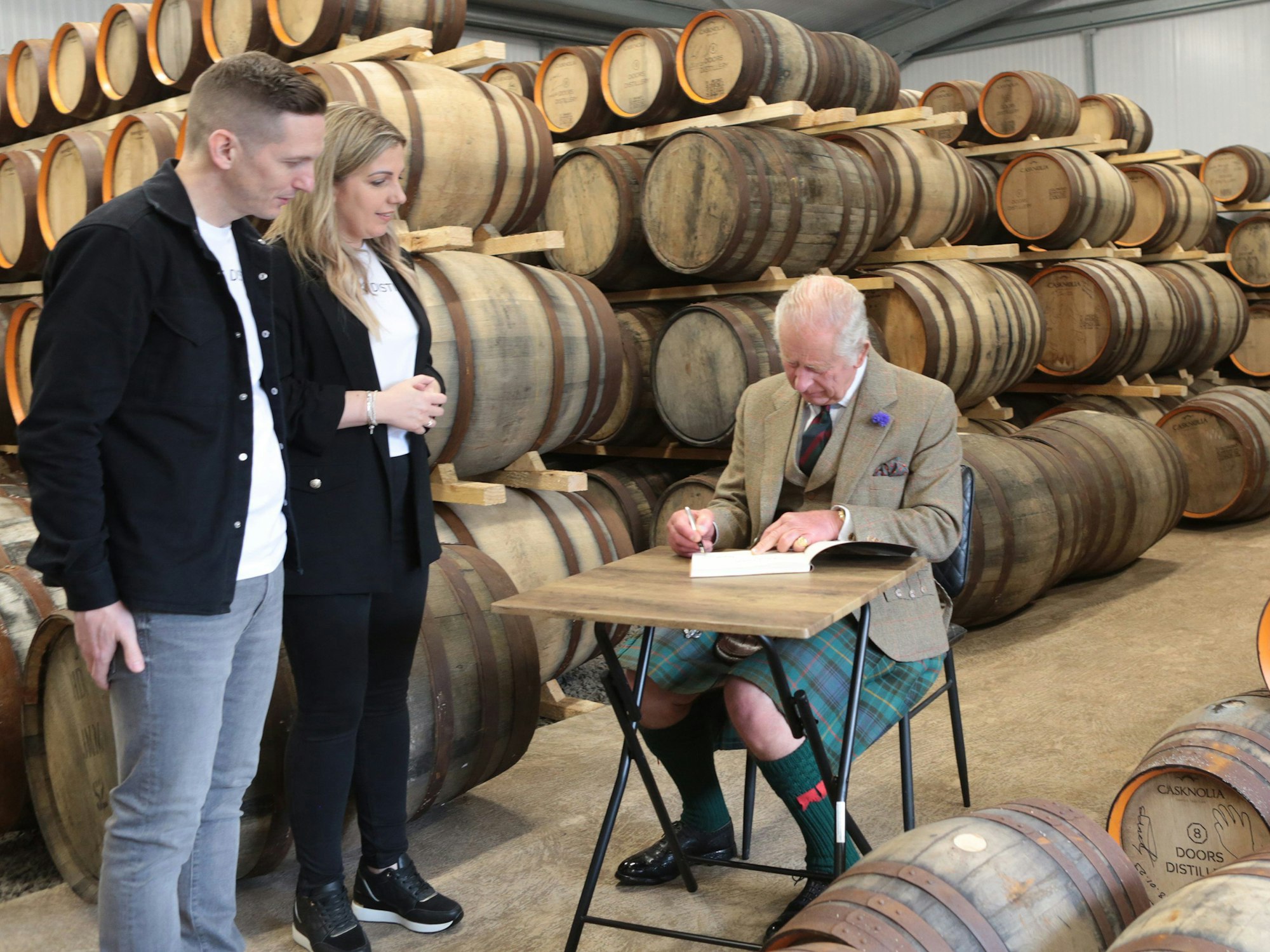 König Charles III. (r) mit den Brennereibesitzern Kerry und Derek Campbell während des Besuchs in der 8 Doors Distillery.