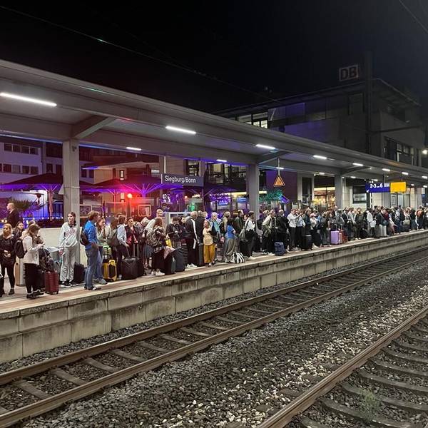 Hunderte Menschen stehen an einem Bahngleis.