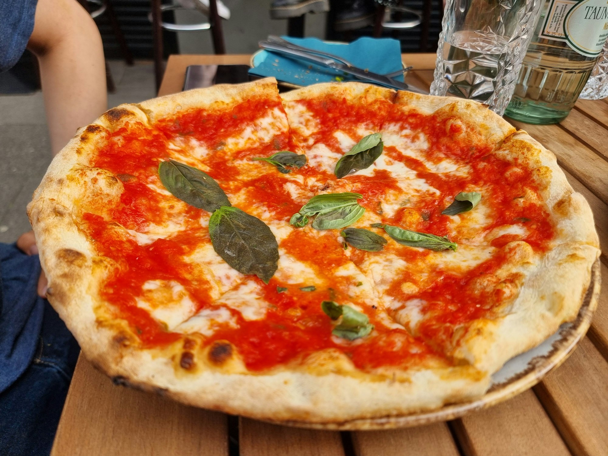 Eine Pizza Margherita liegt auf einem Teller