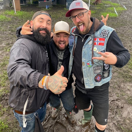 Drei Männer stehen im Schlamm.