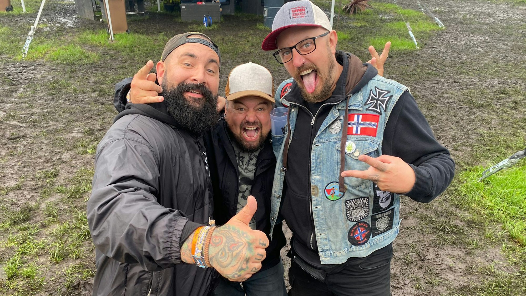 Drei Männer stehen im Schlamm.