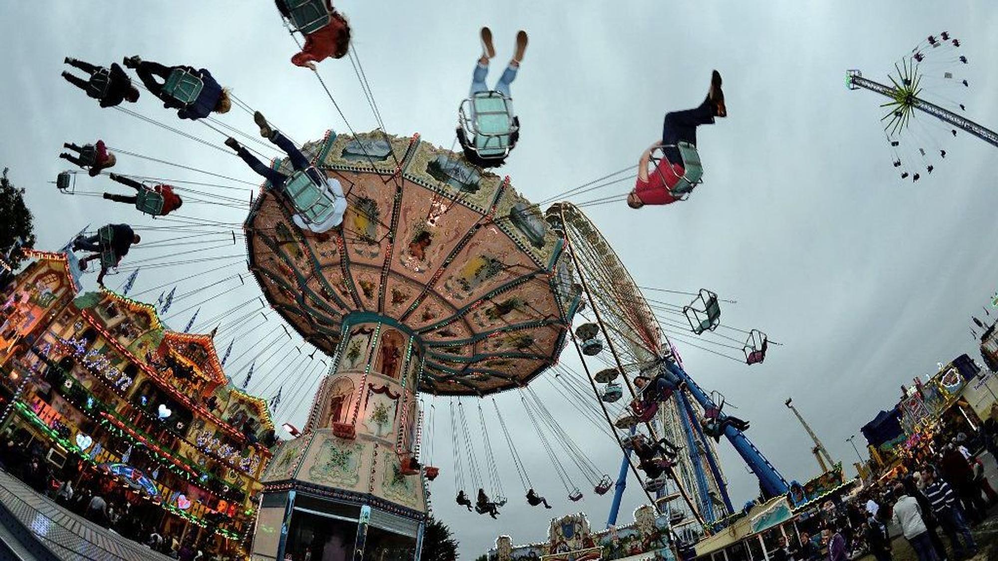 Besucher fahren in Bonn beim Jahrmarkt „Pützchens Markt“ mit einem Kettenkarussell.