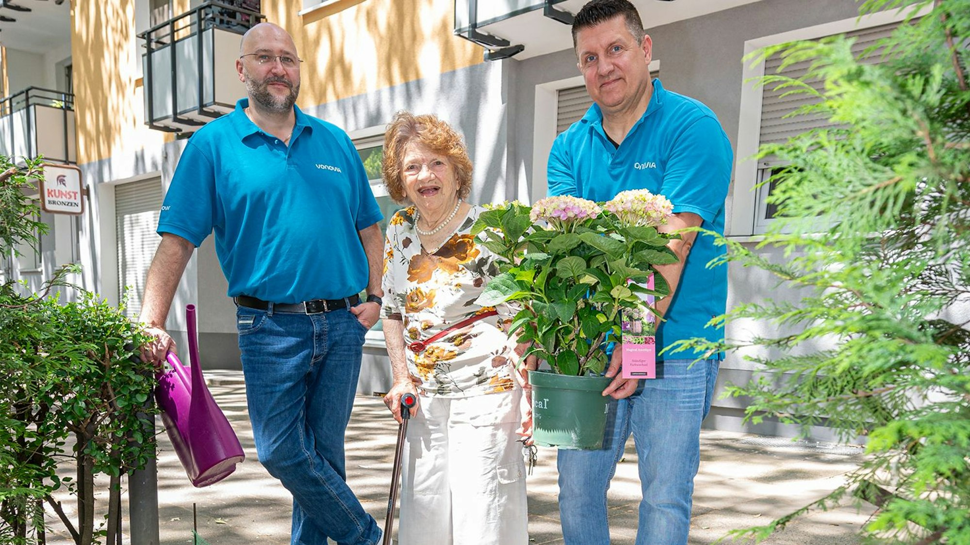 Zwei Vonovia-Mitarbeiter mit Elsa Rothschild und der Hortensie.