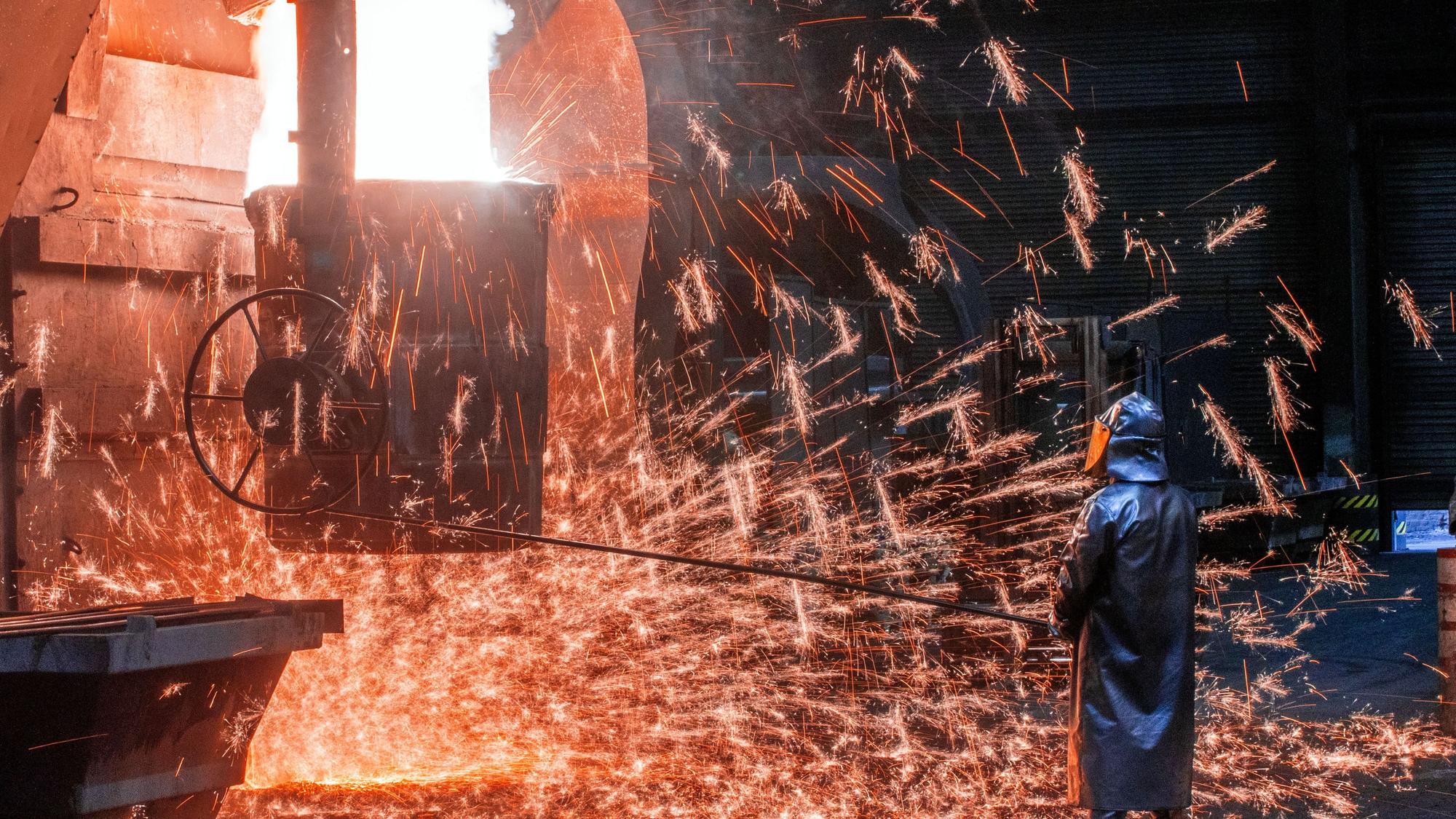 Ein Arbeiter mit Schutzmantel und Helm steht vor sprühenden Funken und kontrolliert die Abfüllungen in einen Transporttopf. Flüssiges Eisen mit einer Temperatur von 1.400 Grad wird in der Eisengießerei Torgelow für das Herstellen von großen Metallteilen vorbereitet. Die bis zu 110 Tonnen schwere Metallteile sind für Windkraftanlagen bestimmt. Die Corona-Krise belastet die Eisengießerei Torgelow GmbH in Vorpommern - einem der wichtigsten Industriebetriebe der Region und nach eigenen Angaben eine der größten Gießereien ihrer Art in Europa.