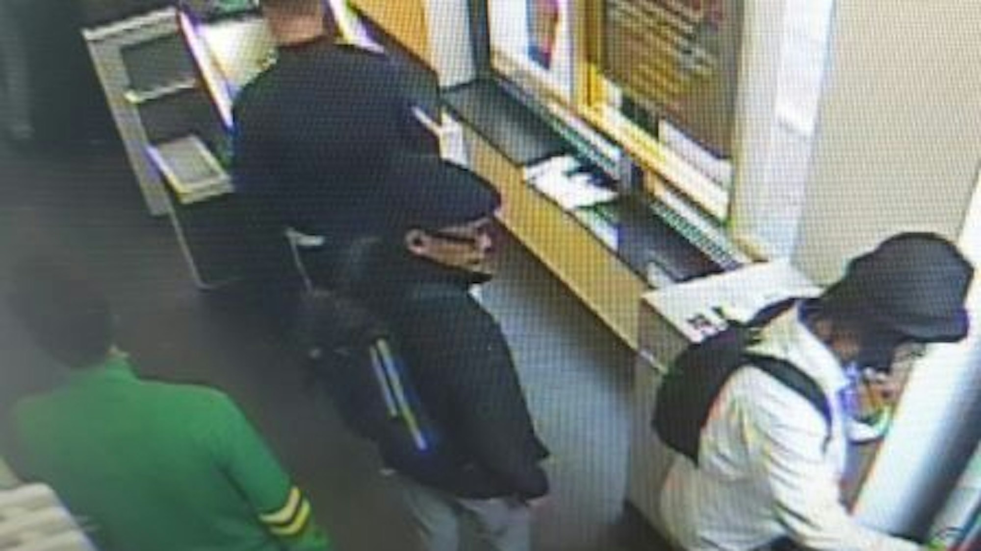 Die Aufnahme einer Überwachungskamera zeigt vier Menschen in einer Bank.