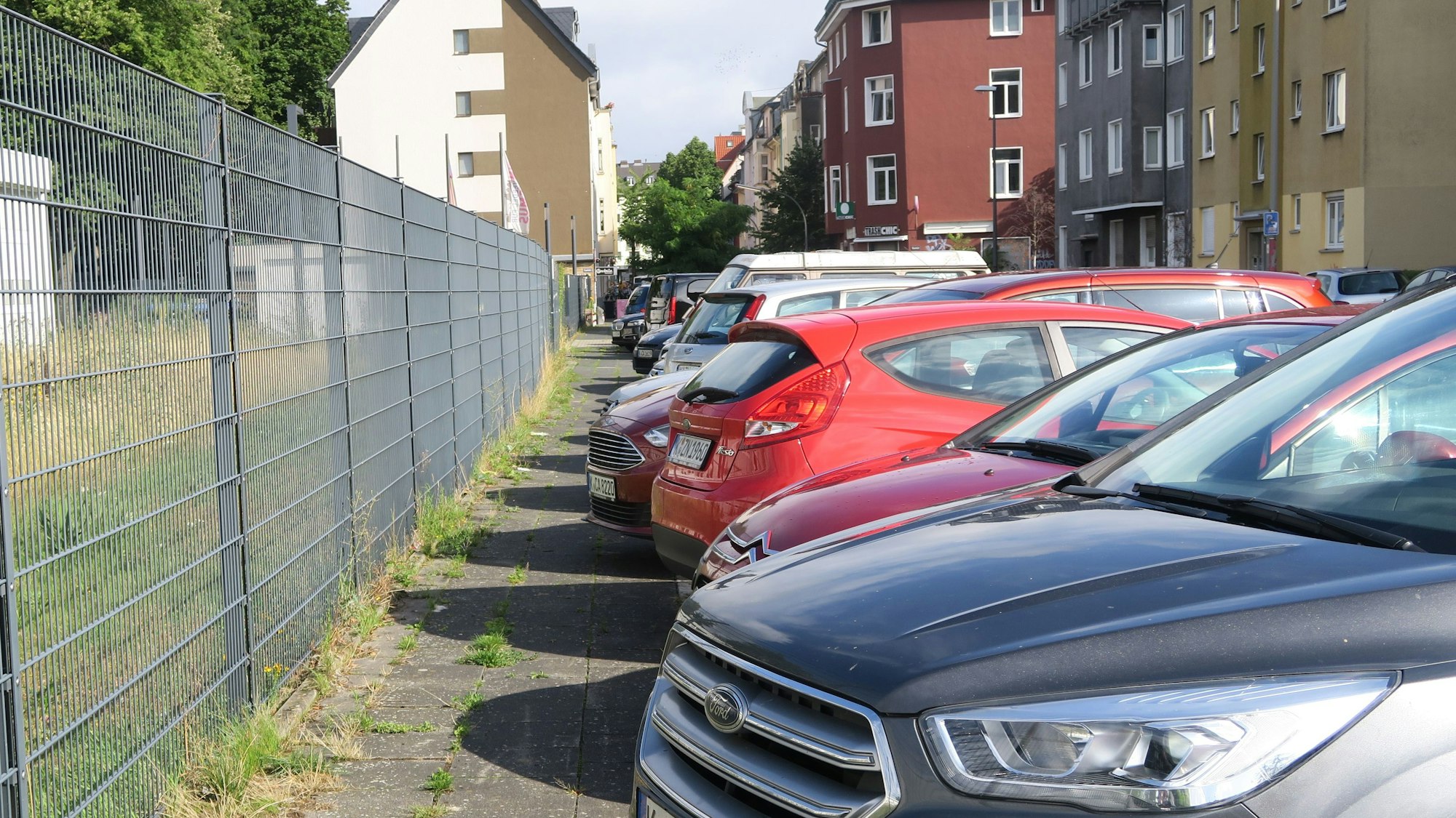 Mehrere Autos parken an einem Zaun.
