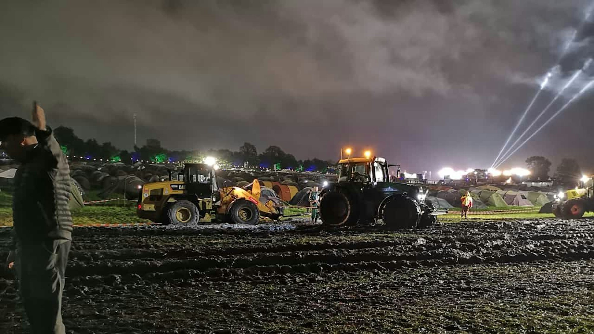 Ein Bagger wird von Traktoren aus dem Schlamm gezogen.