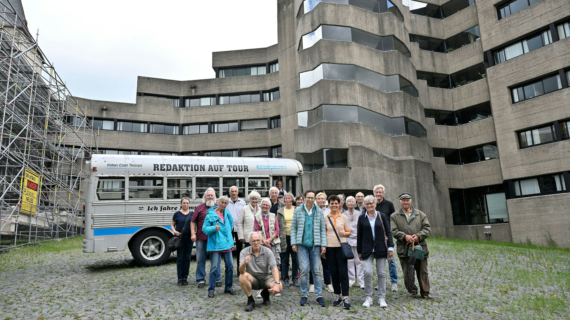 Eine Gruppe und ein historischer Bus stehen im Innenhof des Bensberger Rathauses.