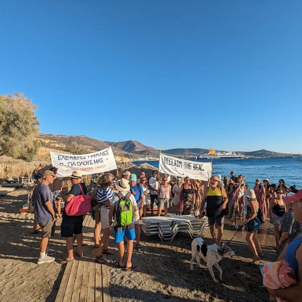 Menschen demonstrieren mit Bannern mit der Aufschrift „Reclaim the beach“ an einem Strand.