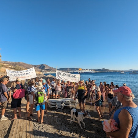 Menschen demonstrieren mit Bannern mit der Aufschrift „Reclaim the beach“ an einem Strand.