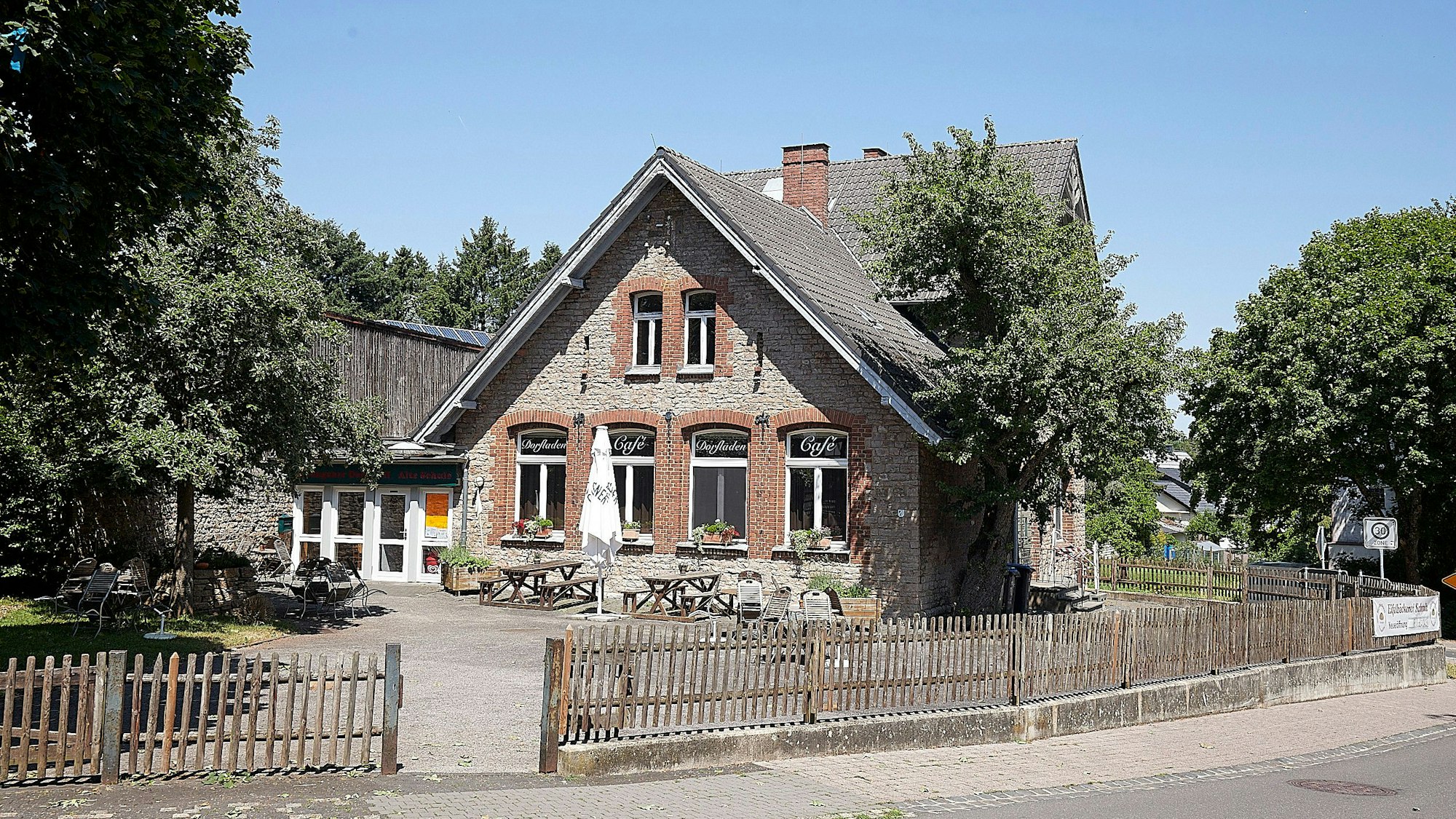 Das Foto zeigt den Dorftreff, der in der Alten Schule untergebracht ist. Davor ungenutzte Tische und Bänke.