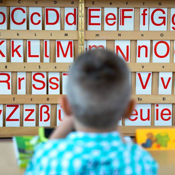 Ein Erklässler sitzt vor einer Buchstabentafel.