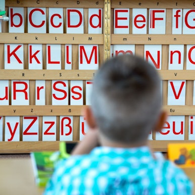 Ein Erklässler sitzt vor einer Buchstabentafel.