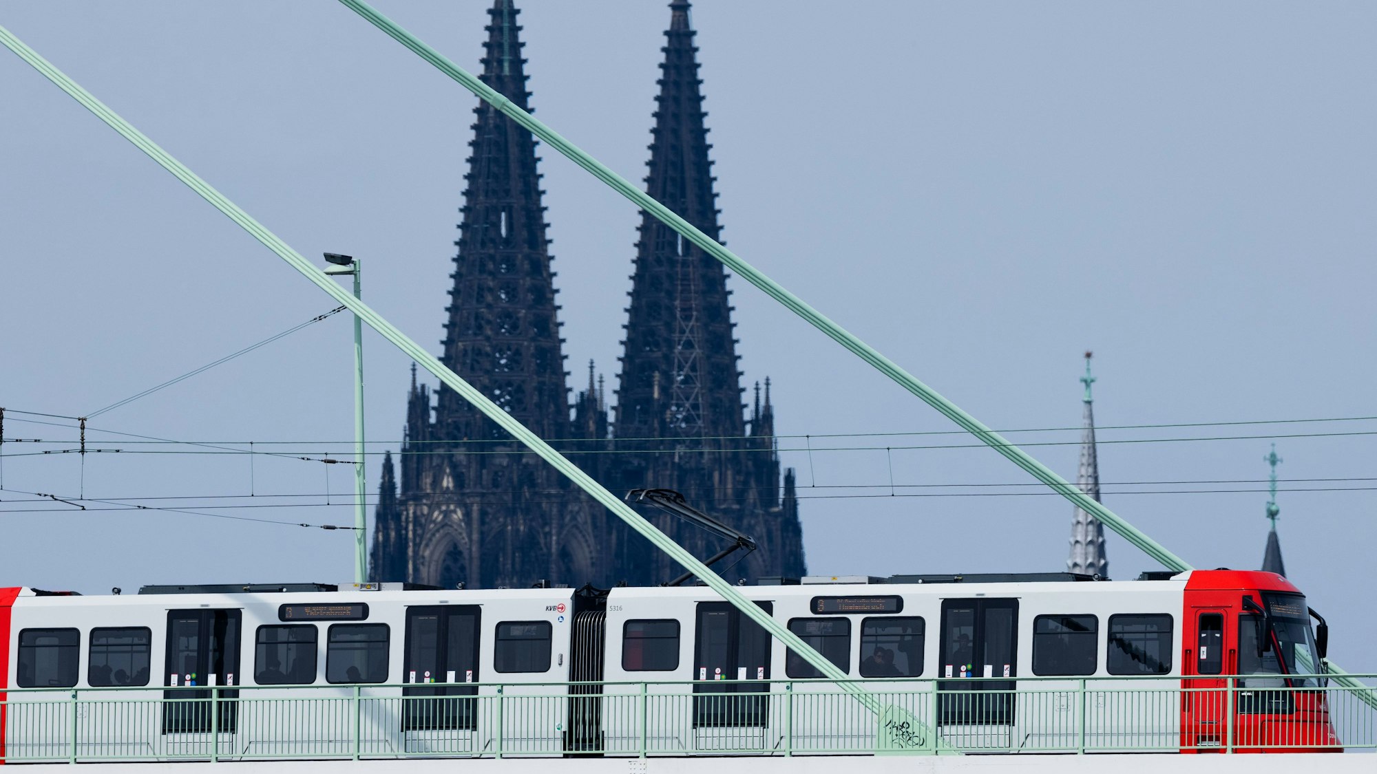 Eine Straßenbahn der Kölner Verkehrsbetriebe (KVB) fährt über die Severinsbrücke vor der Kulisse des Kölner Doms.