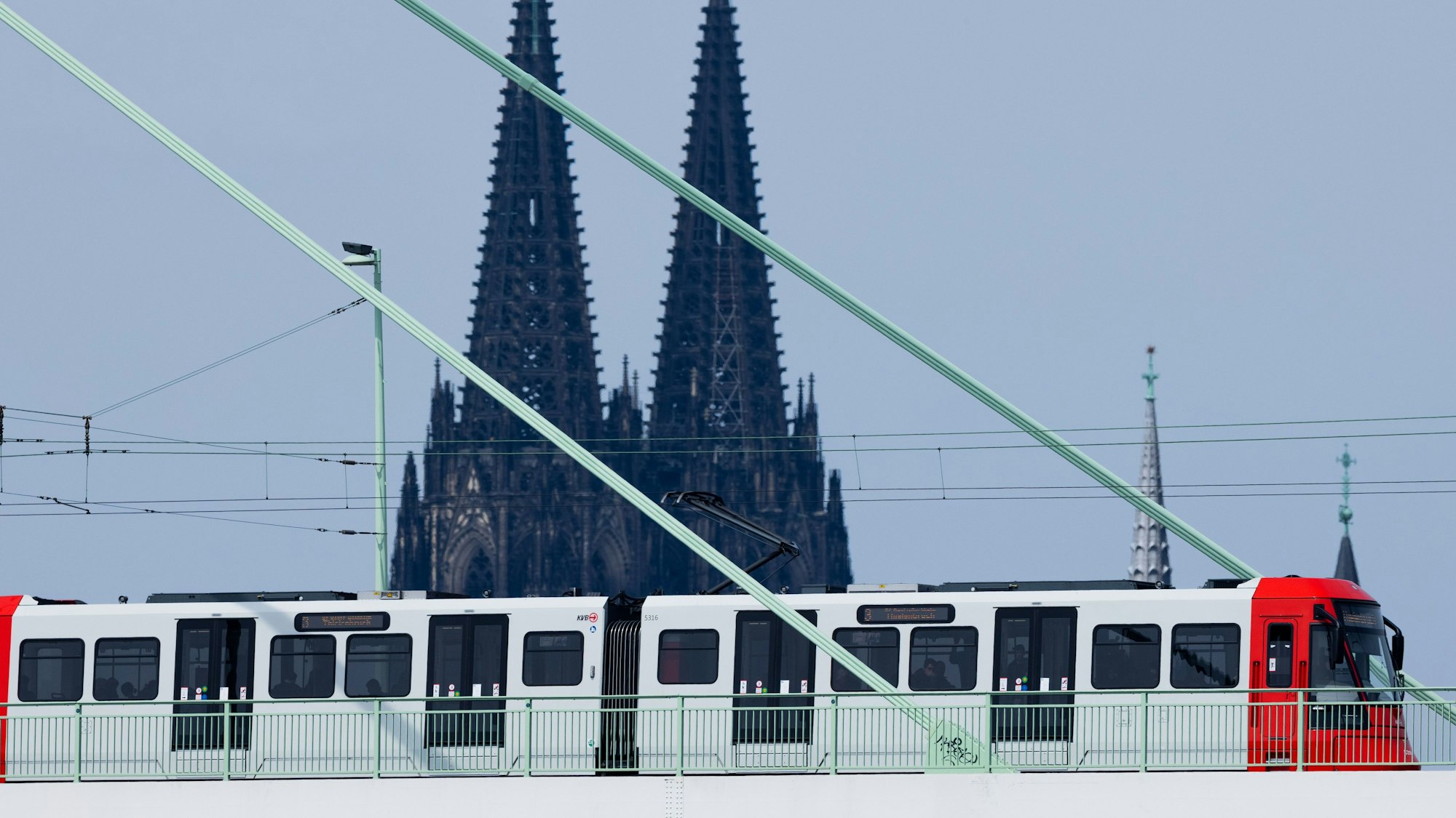 Eine Straßenbahn der Kölner Verkehrsbetriebe (KVB) fährt über die Severinsbrücke vor der Kulisse des Kölner Doms.